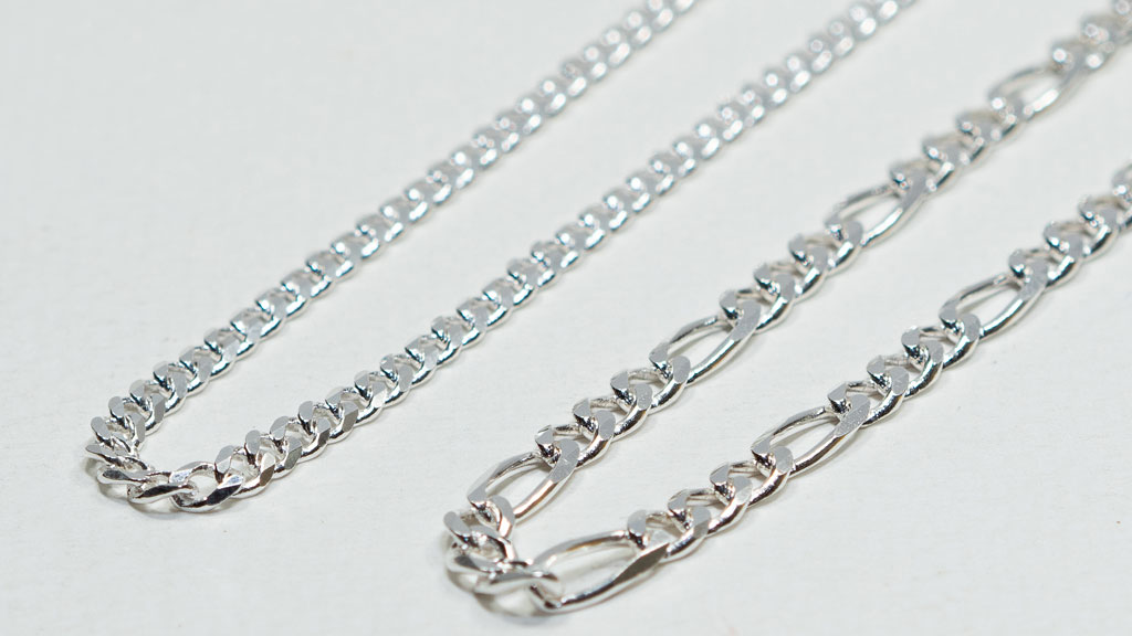 Différents styles de chaînes masculines présentés sur surface bois naturel